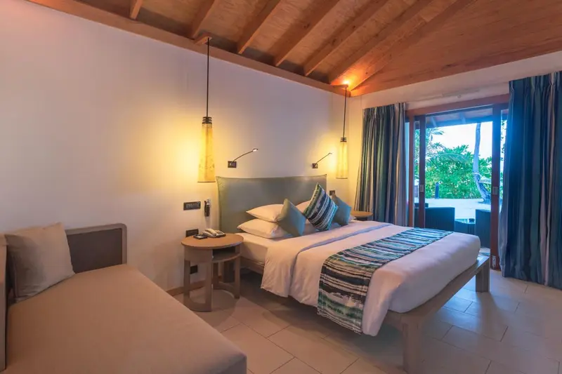 Chambre lumineuse avec un grand lit et un coin salon.