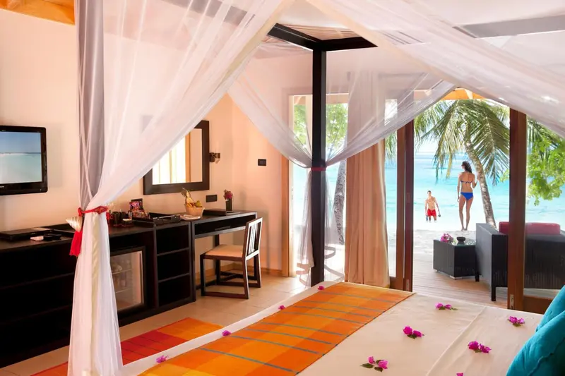 Une chambre lumineuse avec un lit à baldaquin donnant sur une plage.