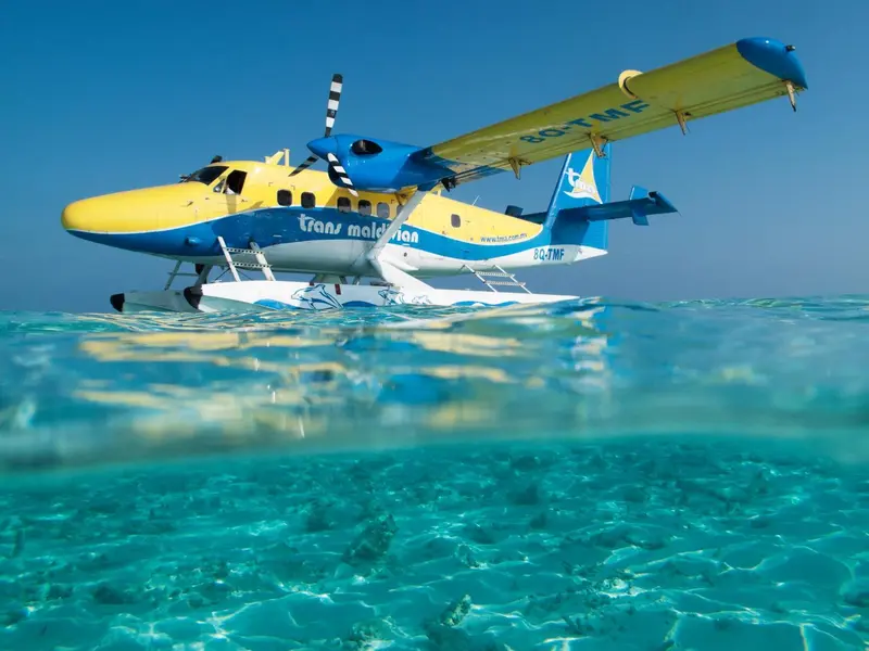Un hydravion jaune et bleu repose sur une eau turquoise et limpide.