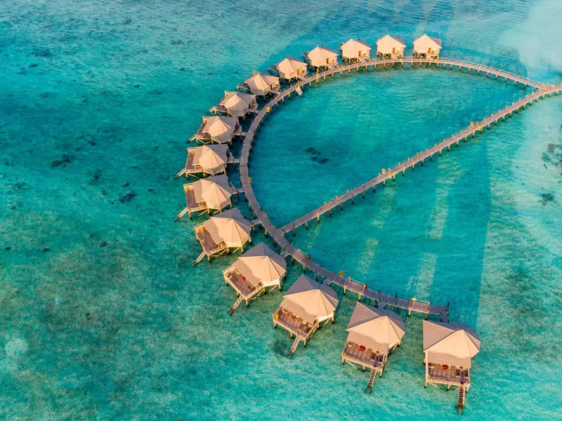 Vue aérienne d'un ensemble de bungalows sur pilotis reliés par une passerelle.