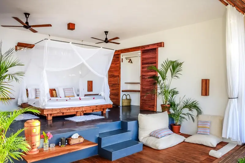 Une chambre lumineuse avec un lit à baldaquin et une décoration tropicale.