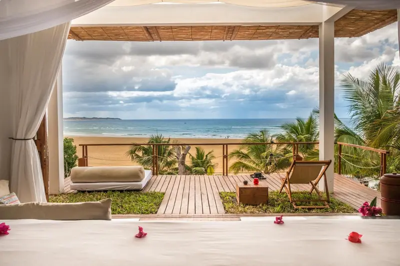 Terrasse en bois avec mobilier d'extérieur donnant sur une plage de sable.