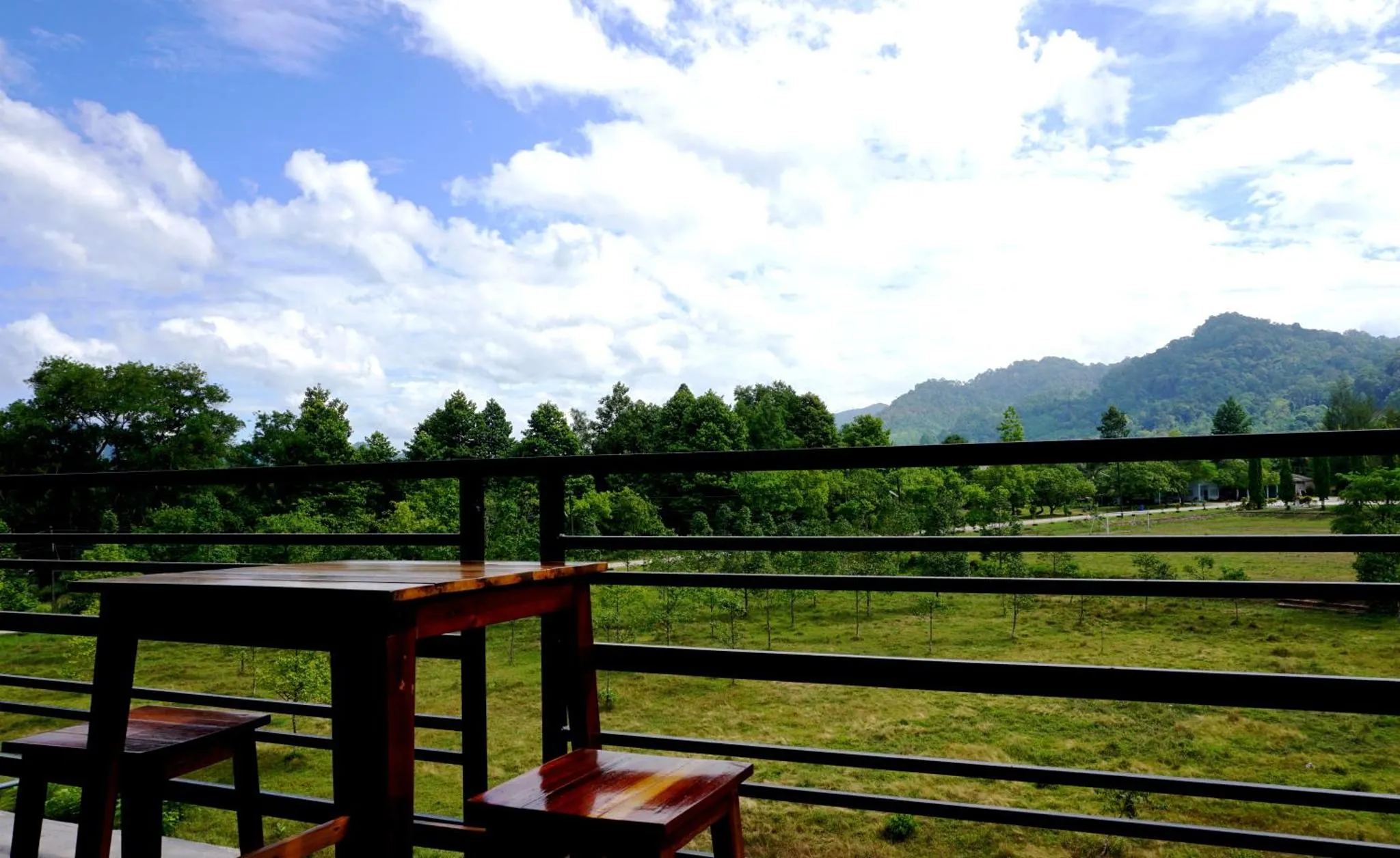 Terrasse avec table et chaises donnant sur un paysage verdoyant et montagneux.
