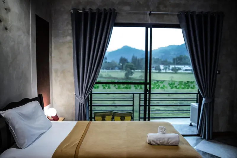 Une chambre avec un grand lit donnant sur un paysage verdoyant.