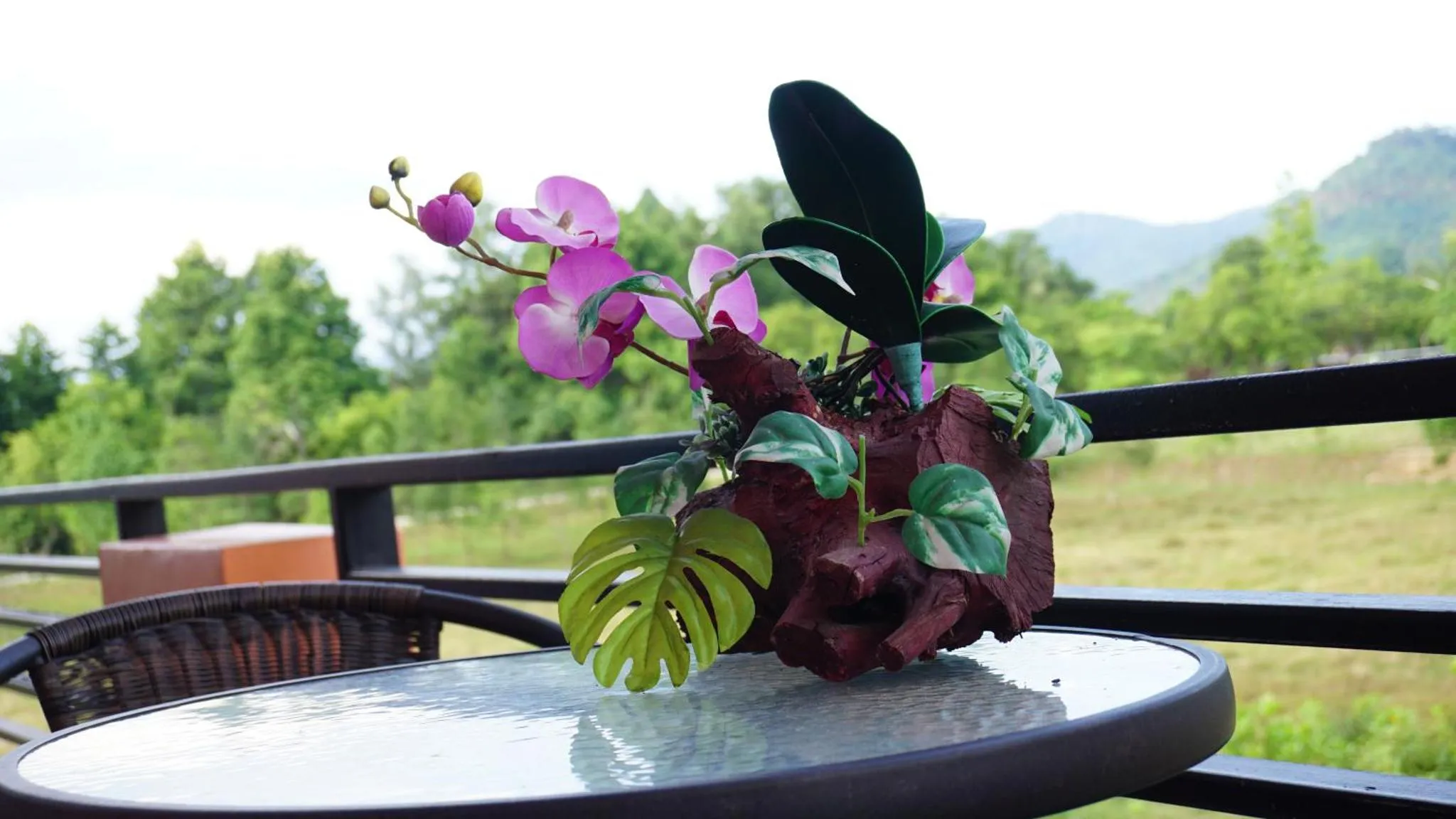 Une composition florale orne une table sur une terrasse.
