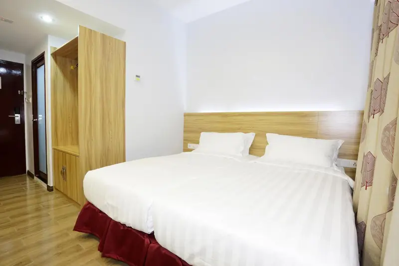 Une chambre avec un grand lit recouvert de draps blancs et un placard en bois.