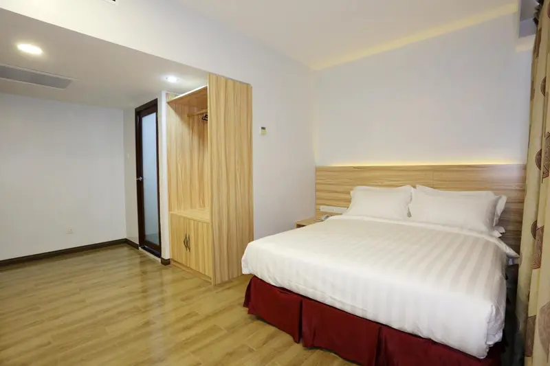 Une chambre lumineuse avec un lit double et un placard en bois.