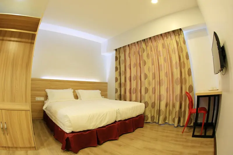 Une chambre lumineuse avec un grand lit et un bureau rouge.