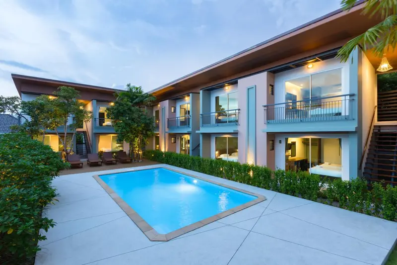 Bâtiment à deux étages avec piscine et végétation luxuriante.