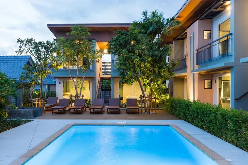 Petite piscine turquoise devant un bâtiment moderne éclairé.