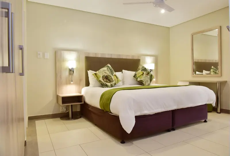 Une chambre lumineuse avec un grand lit recouvert de draps blancs et de coussins.