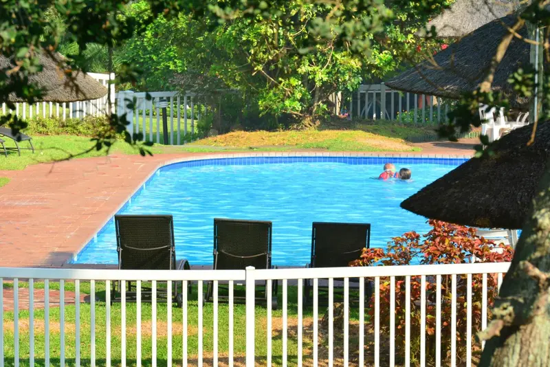 Transats noirs disposés devant une piscine rectangulaire turquoise.