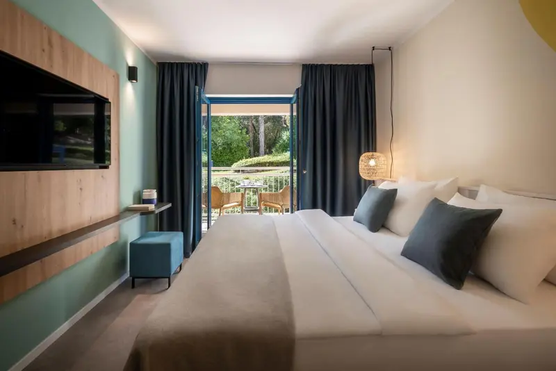 Une chambre lumineuse avec un grand lit et un accès à une terrasse.