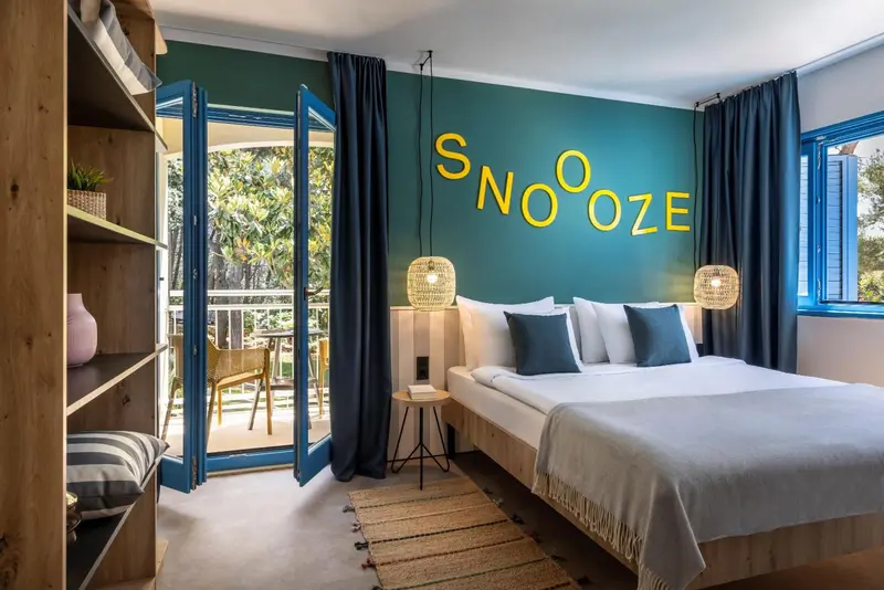 Une chambre lumineuse avec un grand lit et un accès à un balcon.
