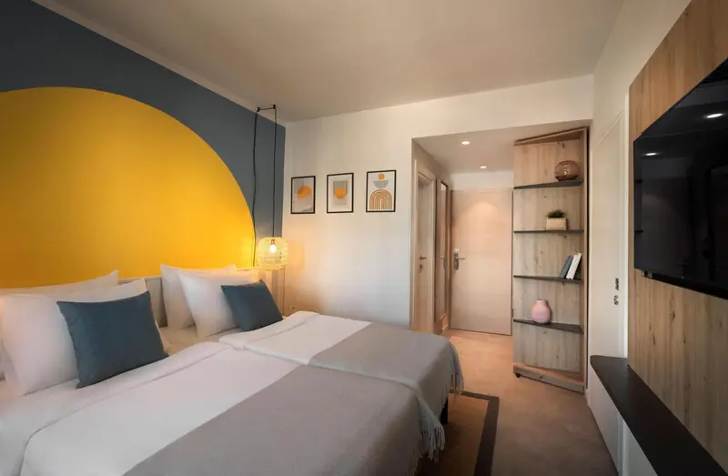 Une chambre lumineuse avec un grand lit et une décoration murale graphique.