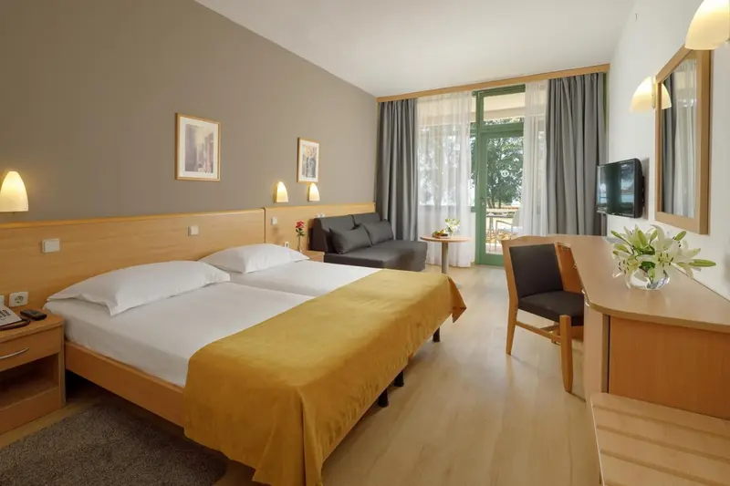 Chambre lumineuse avec un lit double et un coin salon.