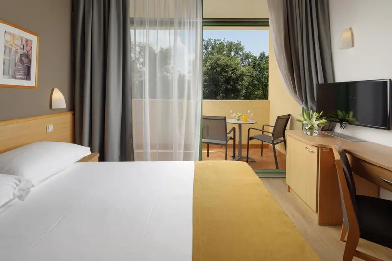 Une chambre lumineuse avec un lit et un accès à un balcon.