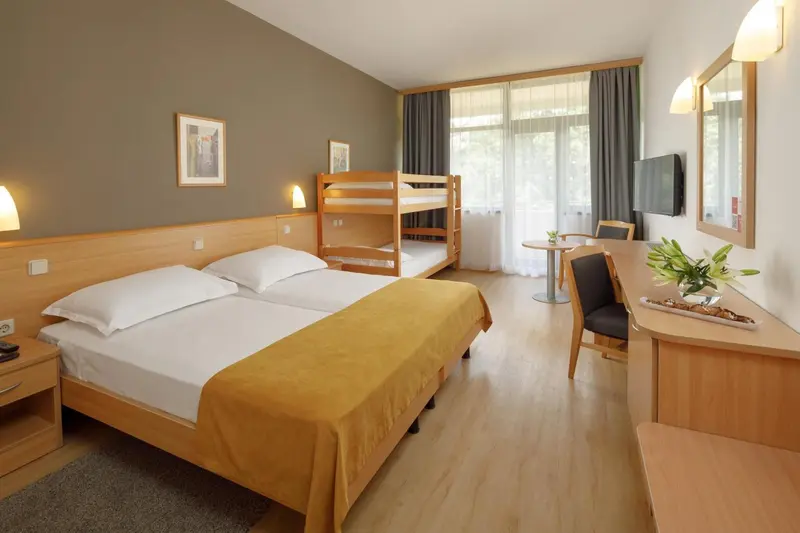 Une chambre lumineuse avec un lit double et un lit superposé.