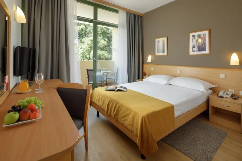 Une chambre lumineuse avec un lit fait et une table garnie de fruits.