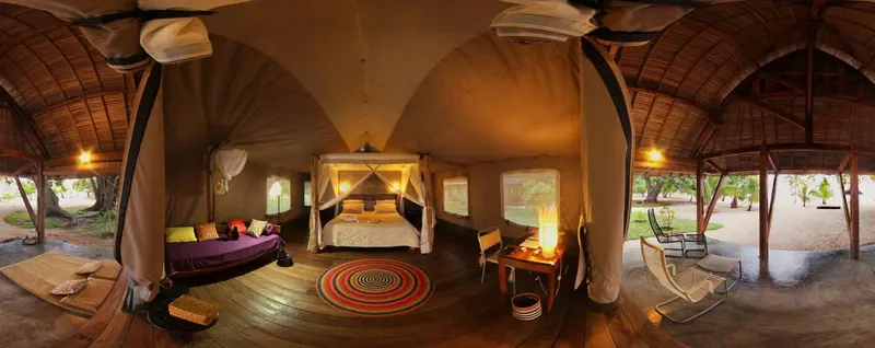 Une tente aménagée en chambre avec un lit et un espace détente.