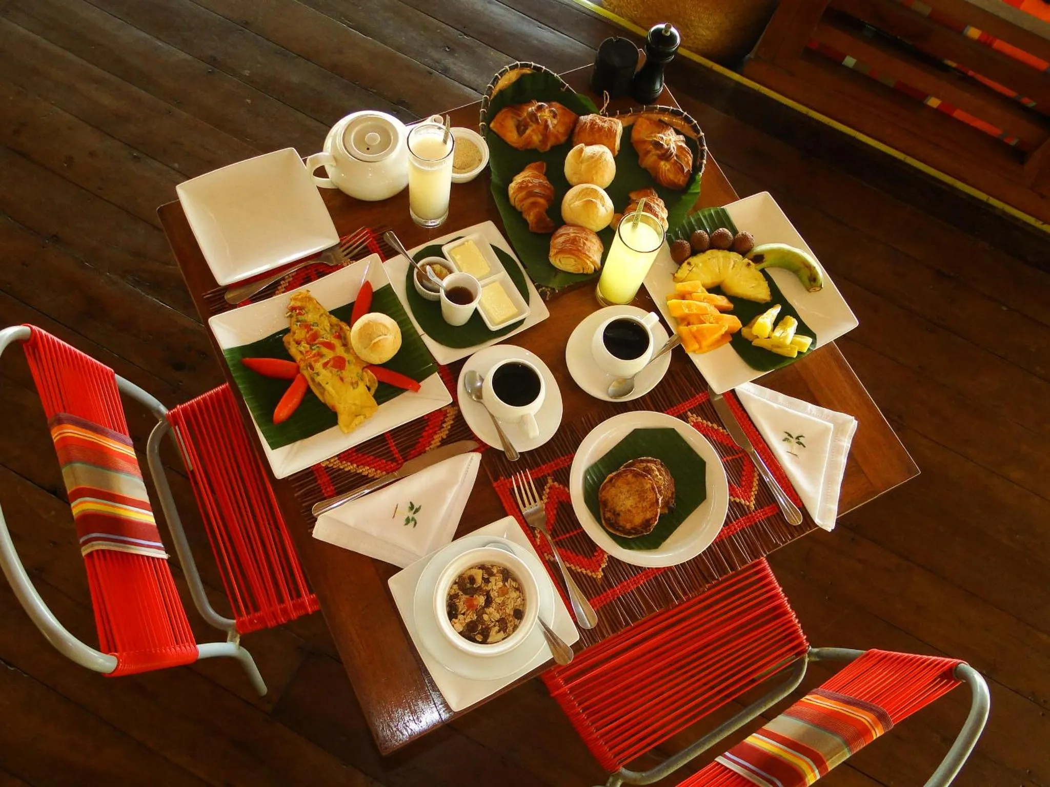 Une table en bois est dressée pour un repas avec des plats variés et des boissons.