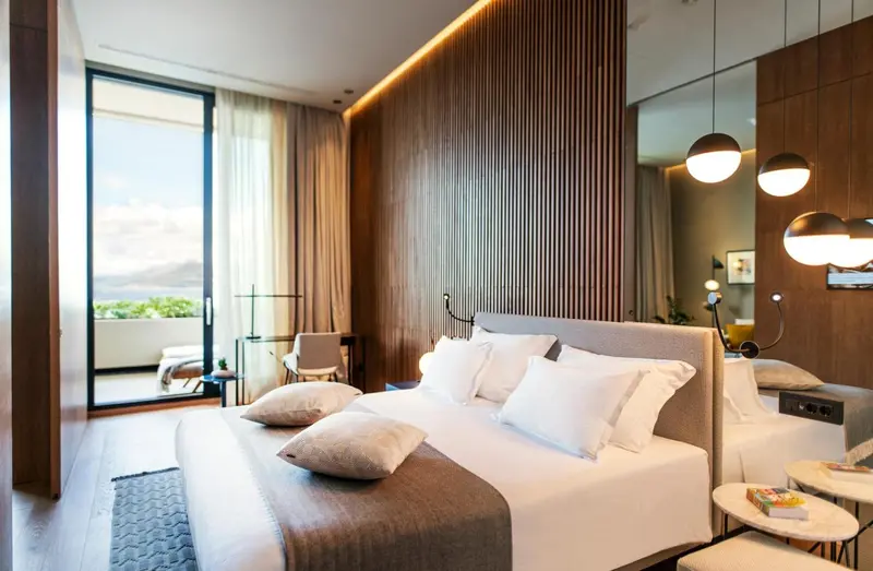 Chambre lumineuse avec un grand lit et une vue sur l'extérieur.