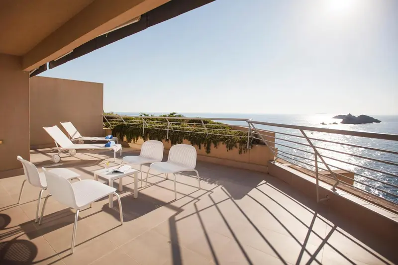 Terrasse aménagée avec mobilier blanc donnant sur la mer.