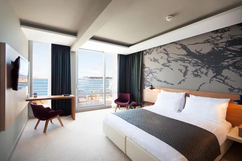 Chambre lumineuse avec un lit double et une vue sur la mer.