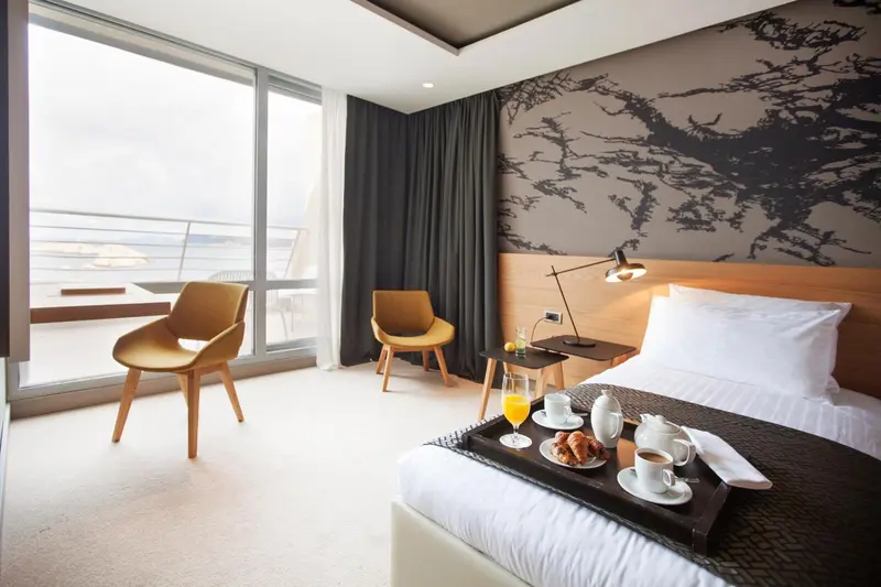 Une chambre lumineuse avec un petit-déjeuner servi sur le lit, donnant sur une vue dégagée.