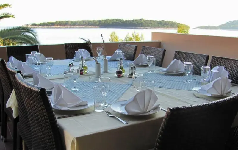 Une table dressée pour un repas en extérieur avec vue sur la mer.
