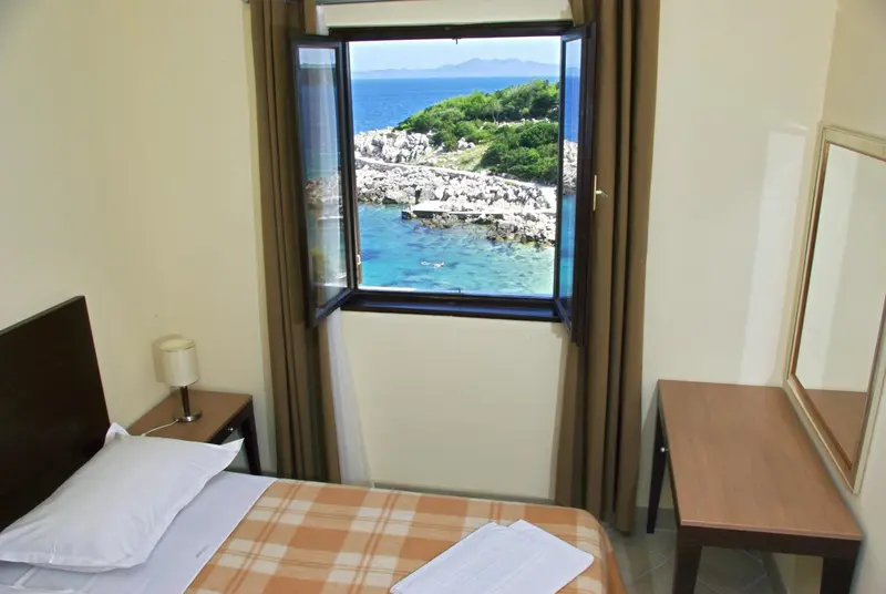 Une chambre lumineuse offre une vue sur la mer et la côte rocheuse.