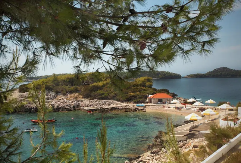 Une crique rocheuse avec une plage et des parasols.