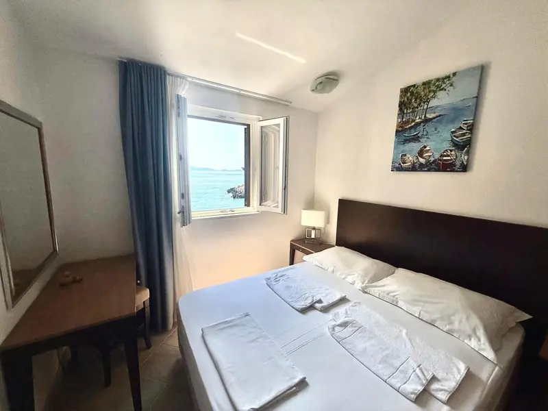 Une chambre lumineuse avec un lit et un bureau donnant sur la mer.