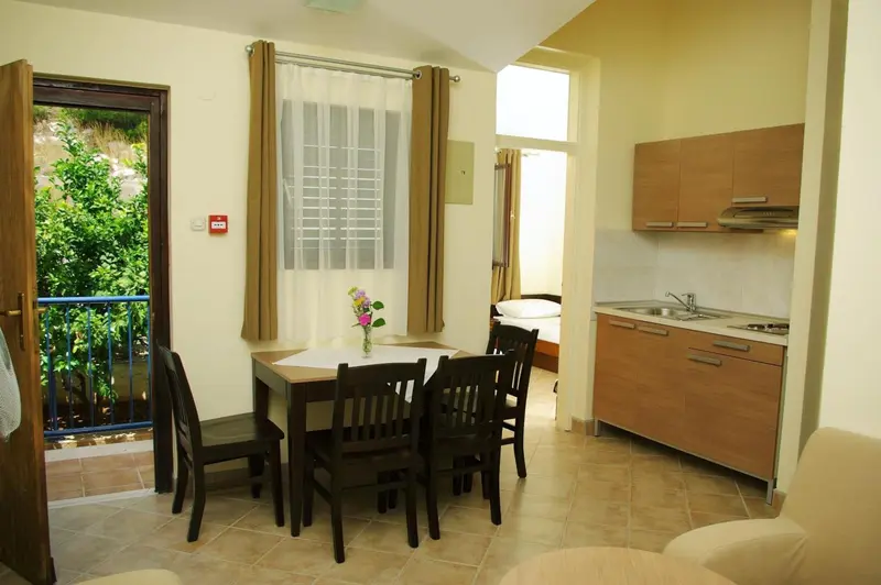Une salle à manger lumineuse avec une table et des chaises près d'une cuisine équipée.