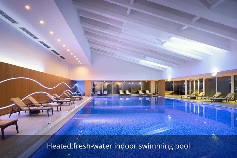 Une piscine intérieure lumineuse avec des transats alignés sur le bord.
