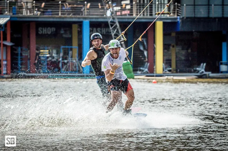 Deux hommes pratiquent le wakeboard sur un plan d'eau agité.
