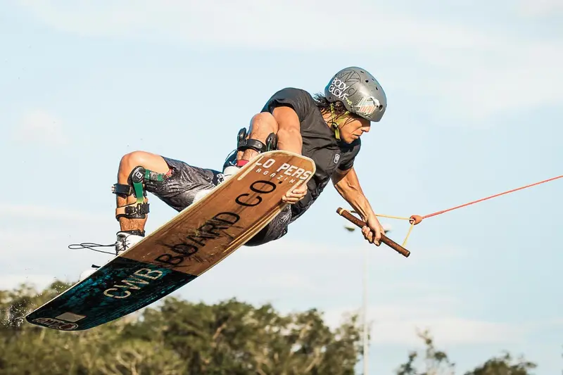 Un homme effectue une figure acrobatique sur une planche de wakeboard en pleine eau.