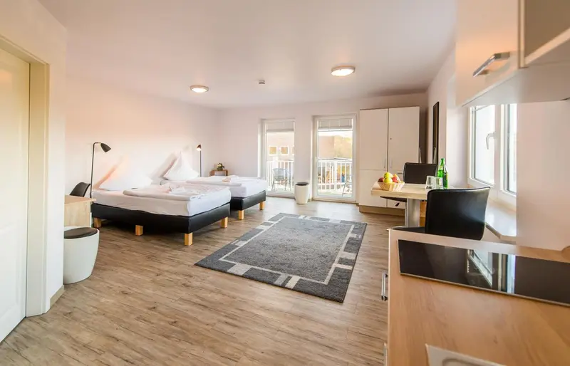 Une chambre lumineuse avec deux lits simples et un coin repas.