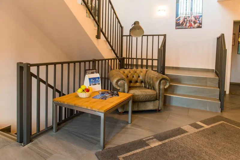 Un fauteuil en cuir et une table basse avec des fruits sont disposés près d'un escalier.