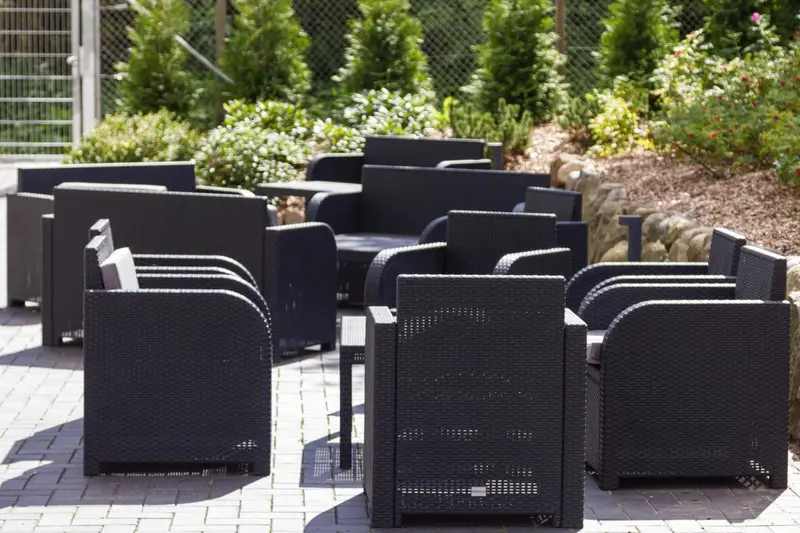 Mobilier de jardin en résine tressée disposé sur une terrasse pavée.