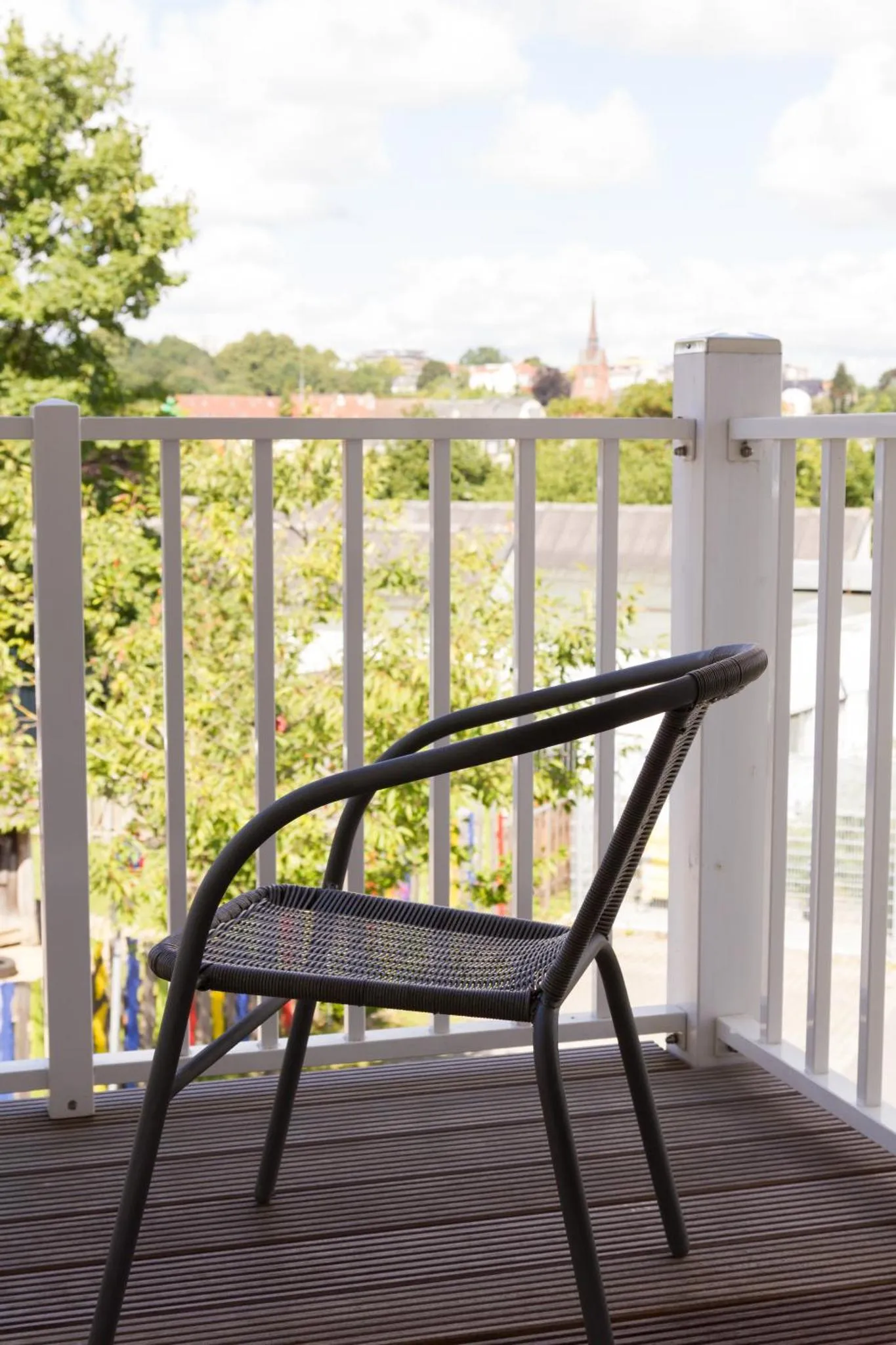 Une chaise en osier sur une terrasse avec vue sur la ville.