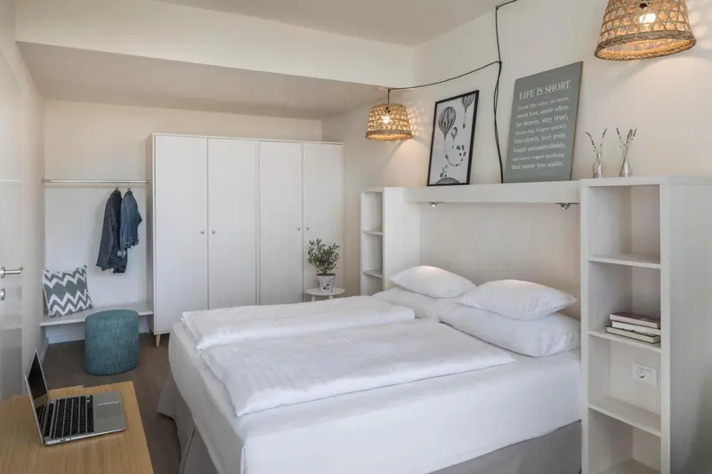 Une chambre lumineuse avec un lit simple et un espace rangement.