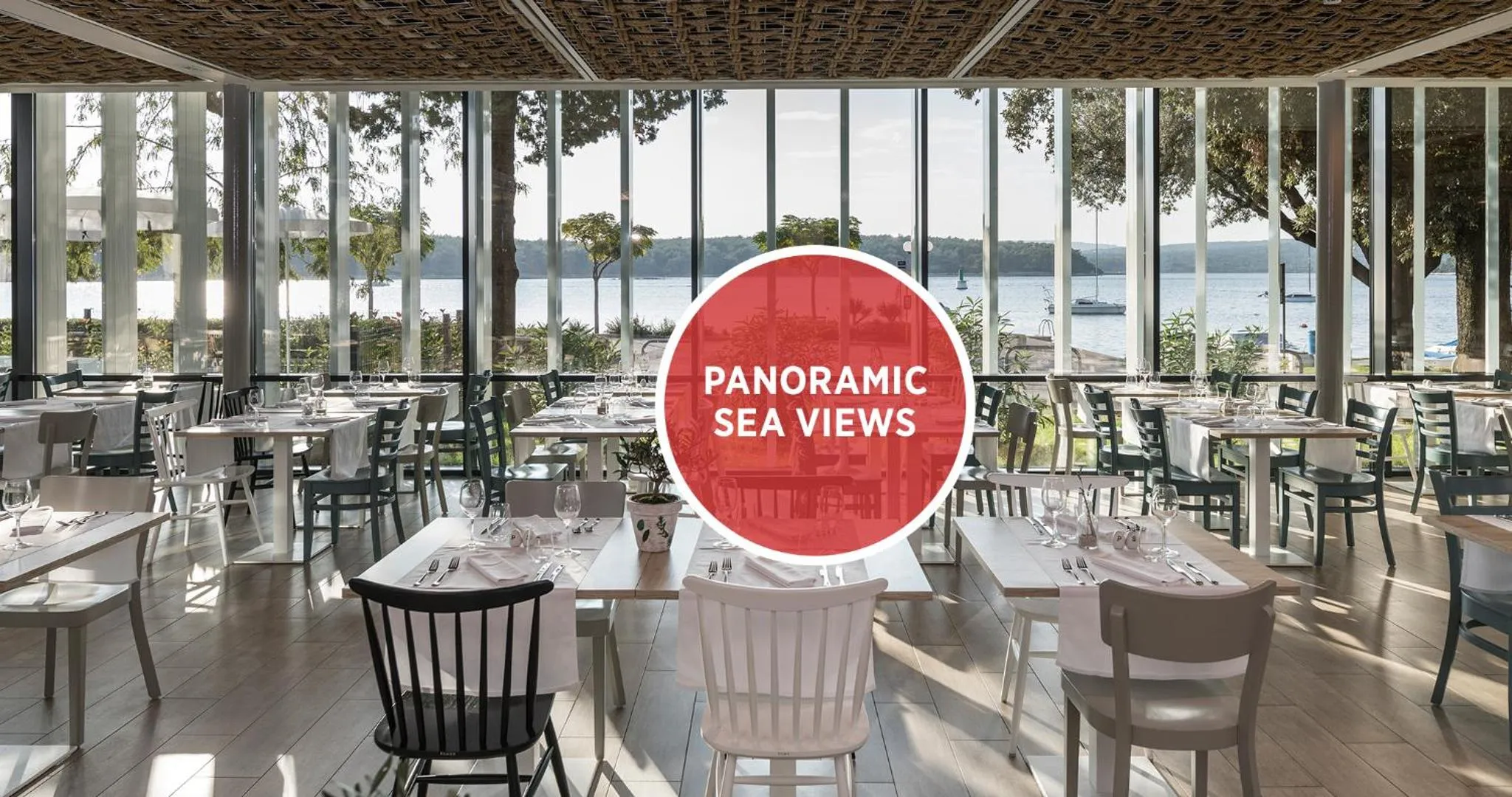 Une salle à manger lumineuse avec de grandes baies vitrées donnant sur la mer.