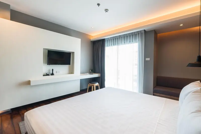 Une chambre lumineuse avec un grand lit et un téléviseur mural.