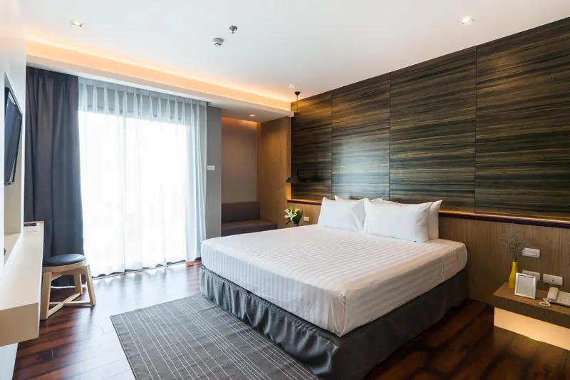 Une chambre lumineuse avec un grand lit et un rideau gris.