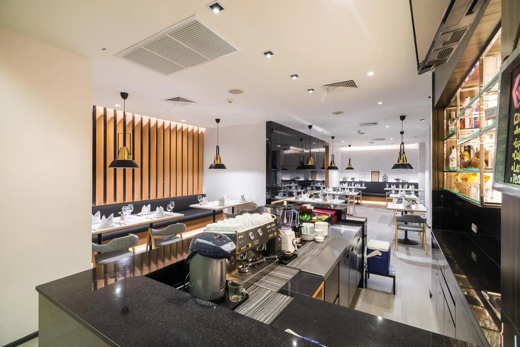 Une salle lumineuse avec des tables dressées et un comptoir de bar.