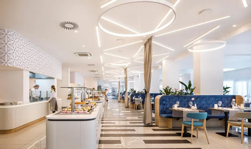 Une salle lumineuse avec un buffet et des tables pour les repas.