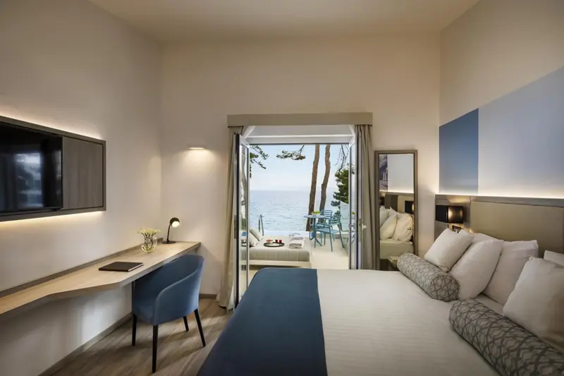 Chambre moderne avec un lit confortable et vue sur la mer depuis une terrasse.
