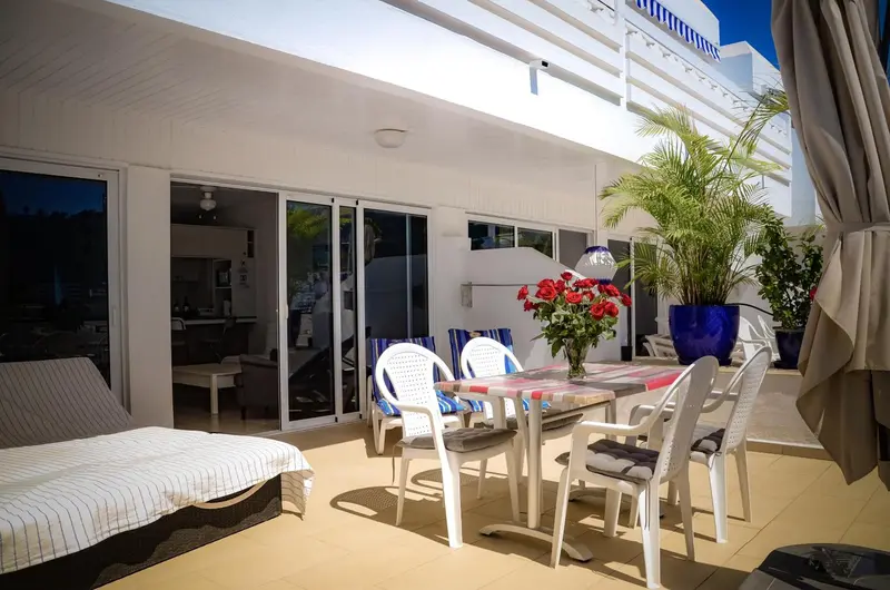 Terrasse aménagée avec mobilier de jardin et vue sur un intérieur clair.