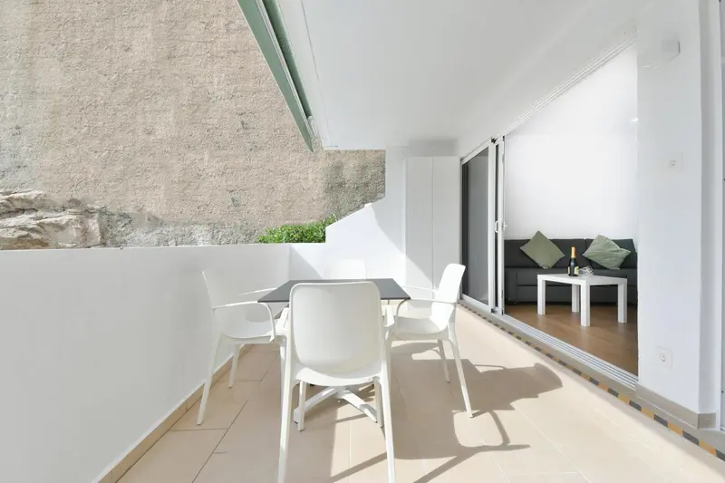 Terrasse avec table et chaises donnant sur un espace salon.